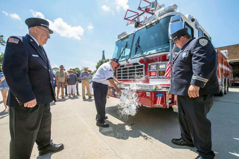 Long time member Mitchell Mezieneski welcomes the new Mack Company Quint Ladder 7-2-1 Chief Tim Sieger and Mack Company Officer Joey Hernandez stand by. 
